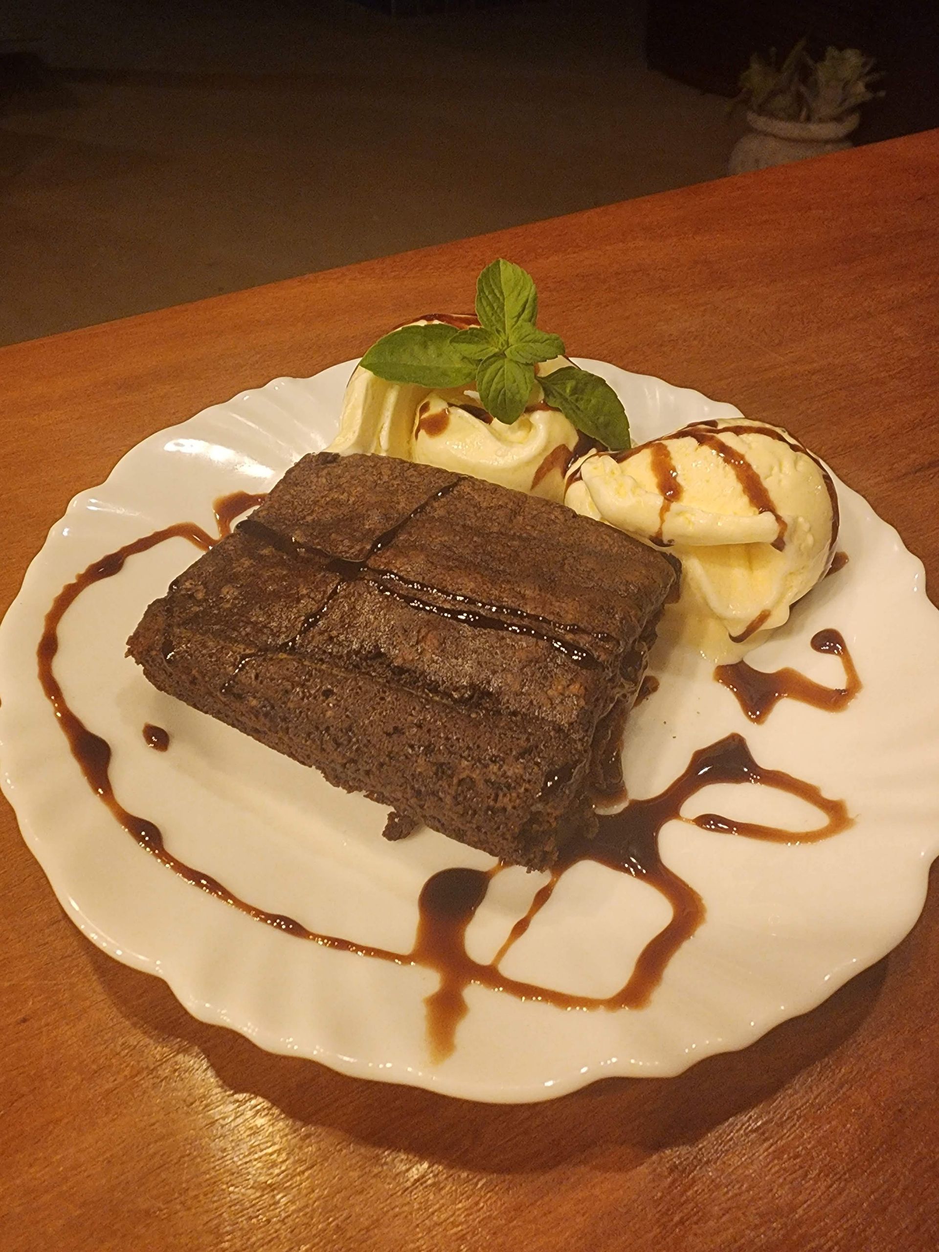 Um prato branco coberto com um brownie e sorvete
