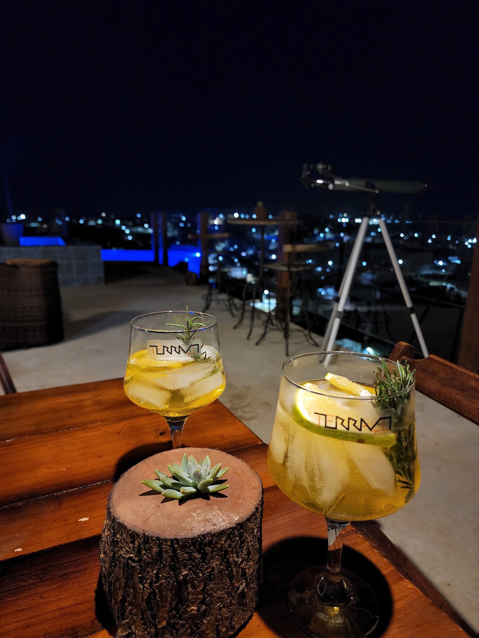 Duas bebidas estão sobre uma mesa de madeira à noite.