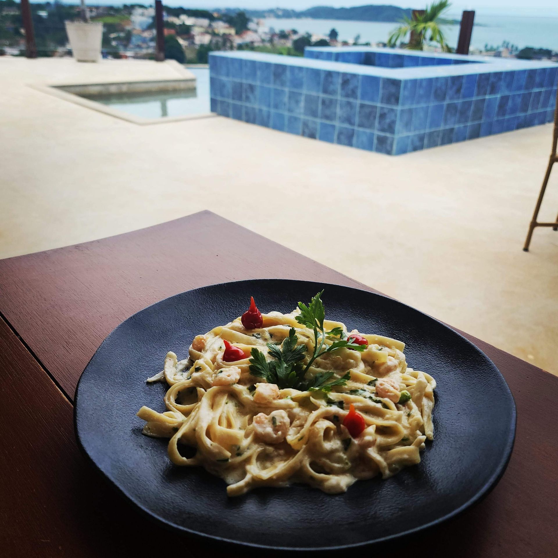Um prato de macarrão com uma piscina ao fundo