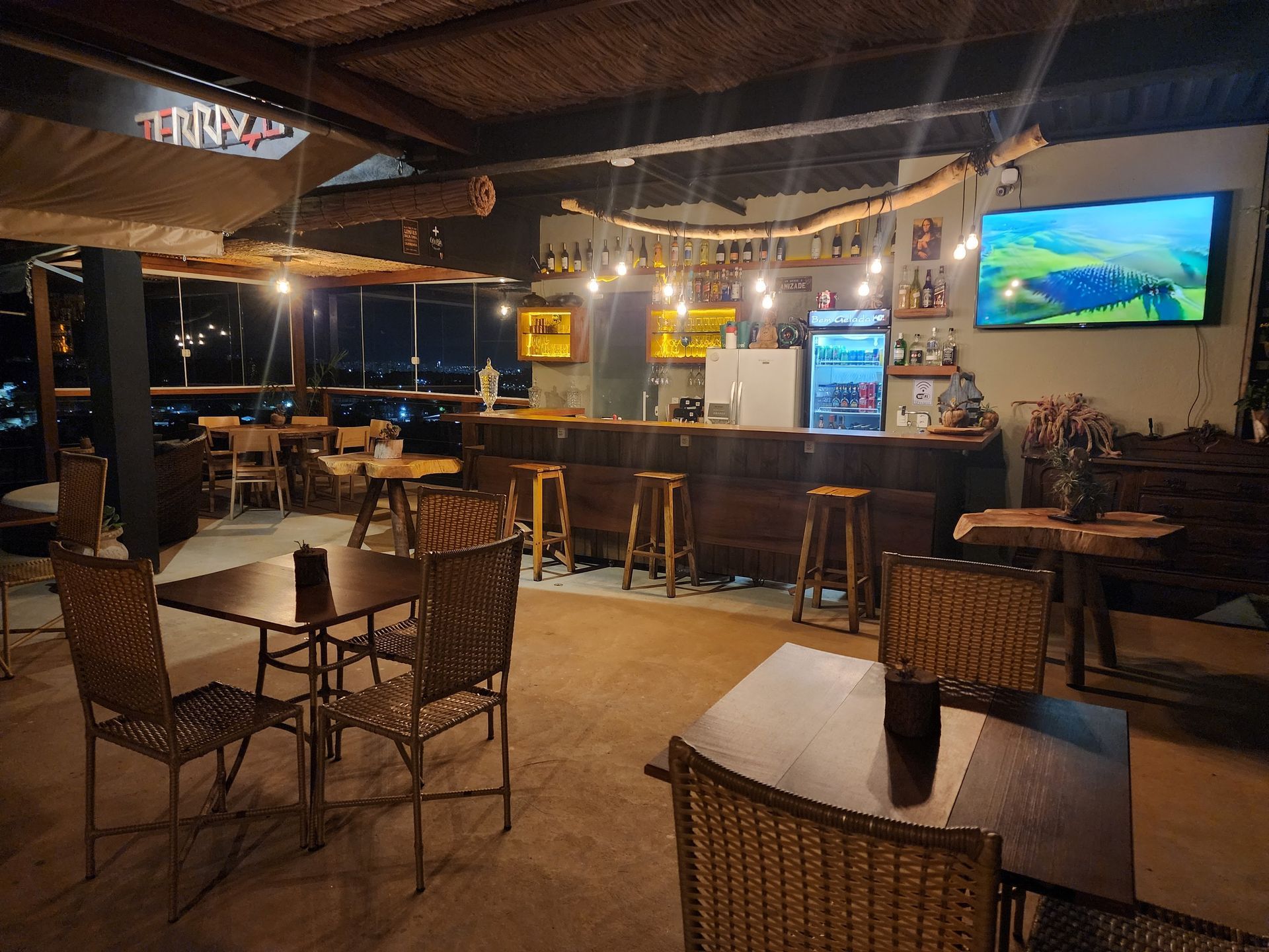 Um restaurante com mesas e cadeiras e uma televisão na parede.