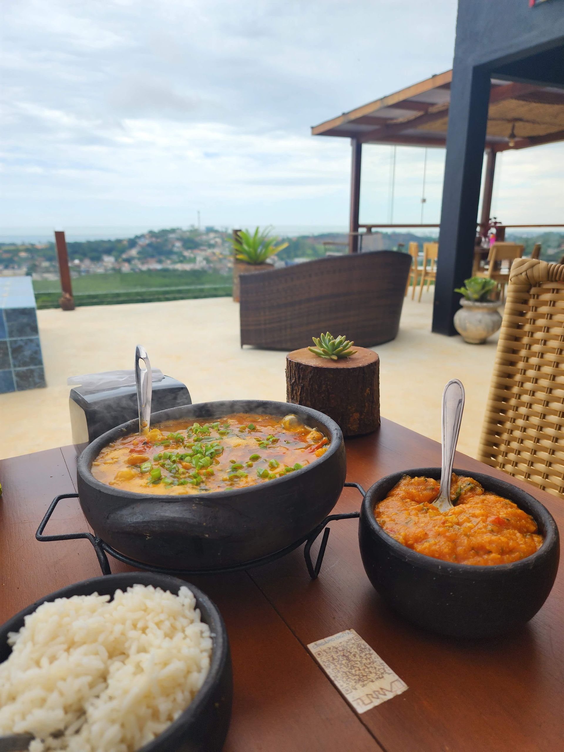 Três tigelas de comida estão sobre uma mesa de madeira.