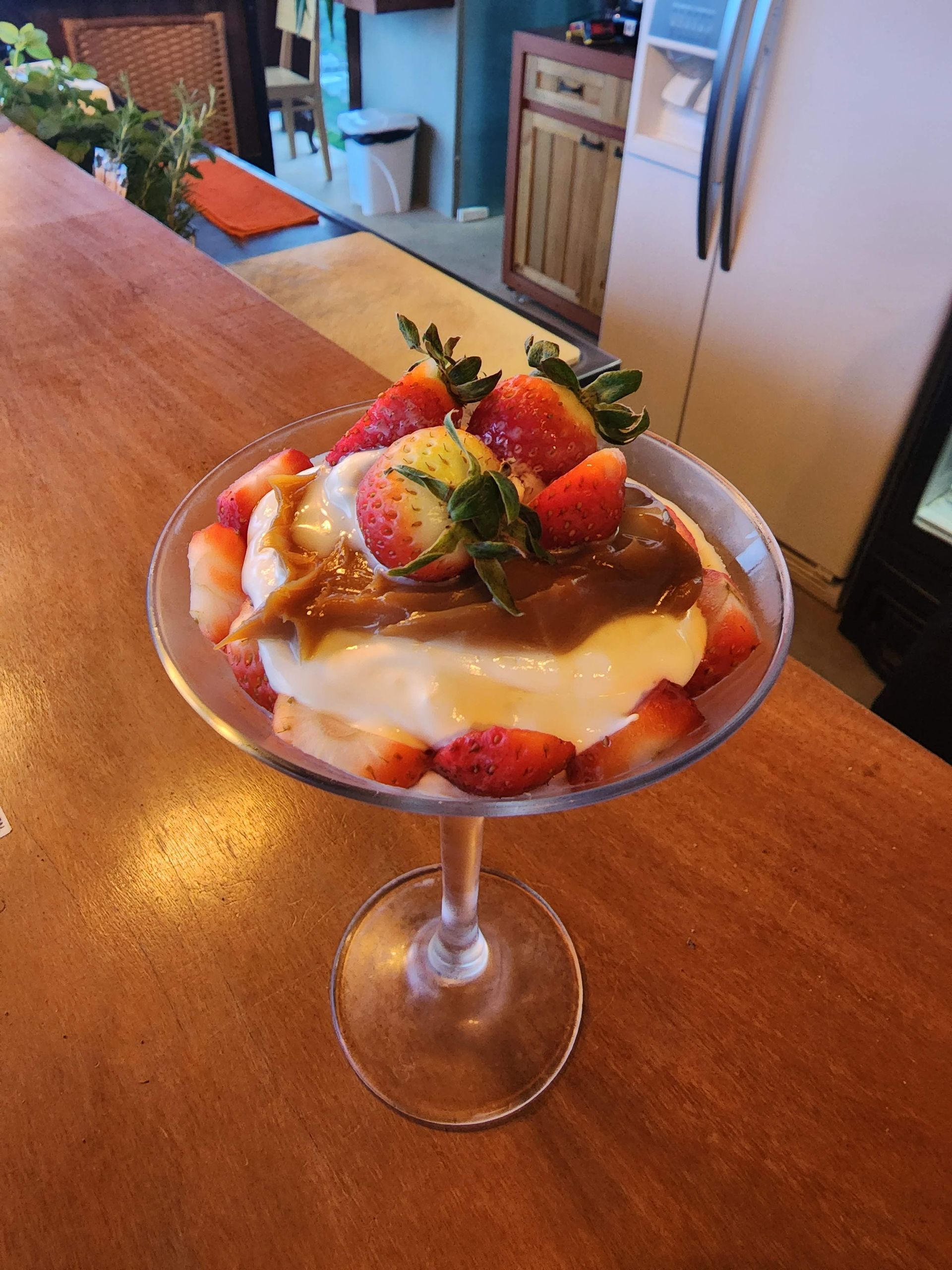 Uma sobremesa em uma taça de vinho com morangos por cima