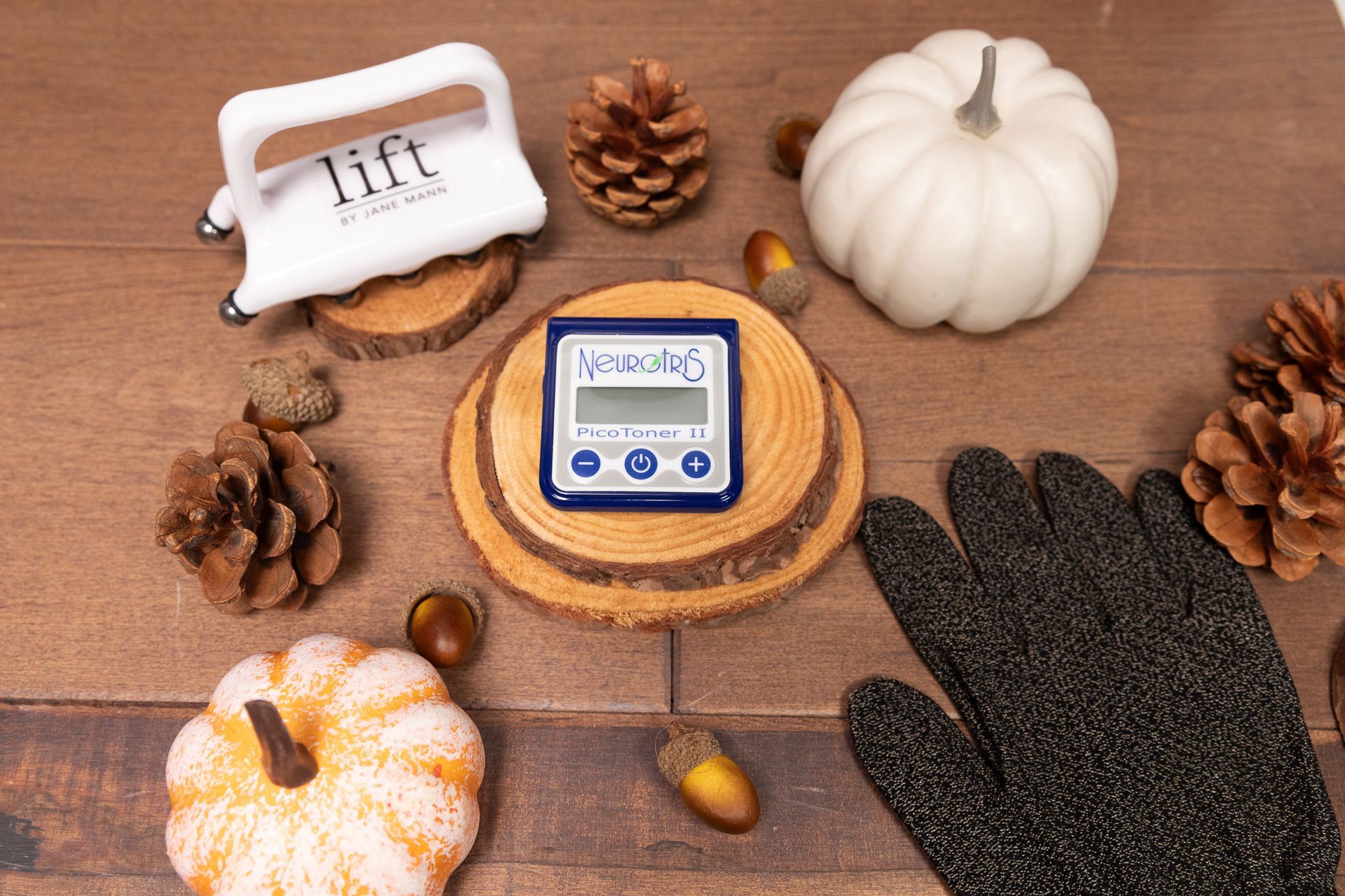 A wooden table topped with pumpkins , pine cones , acorns and a glove.