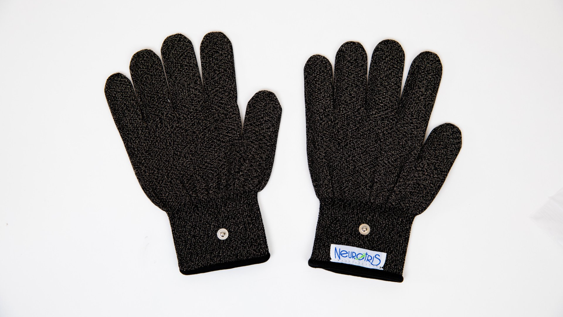 A pair of black gloves are sitting on a white surface.