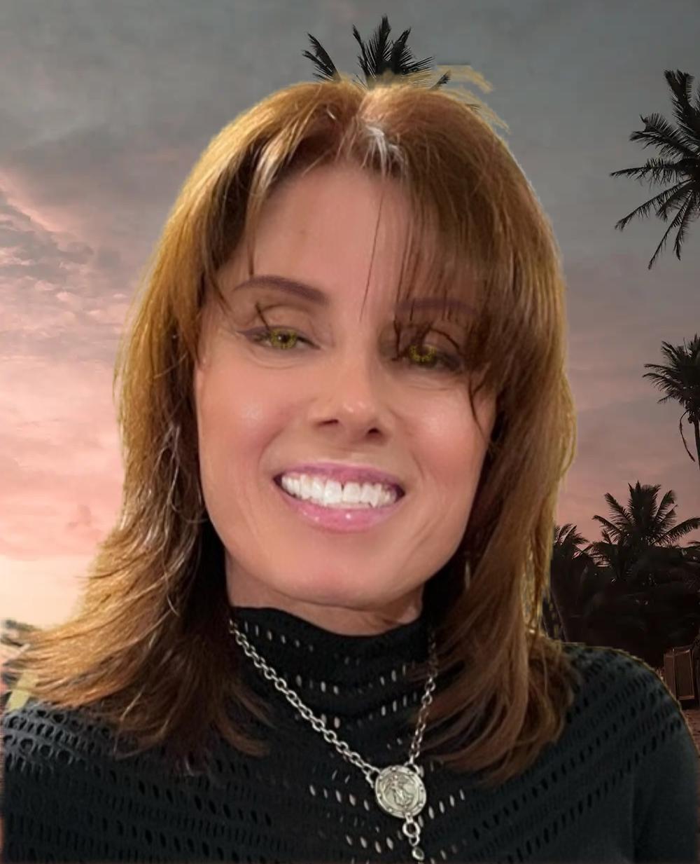 A woman wearing a black top and a necklace smiles for the camera