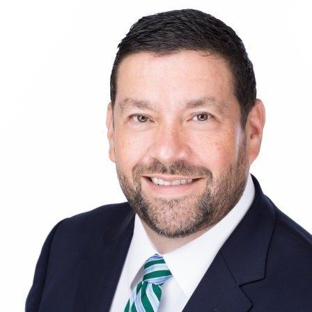 A man in a suit and tie is smiling for the camera