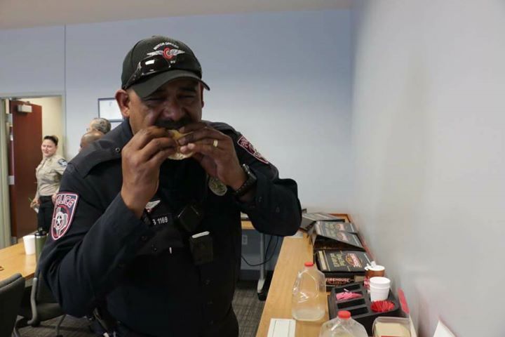 A police officer is eating a sandwich in a room.