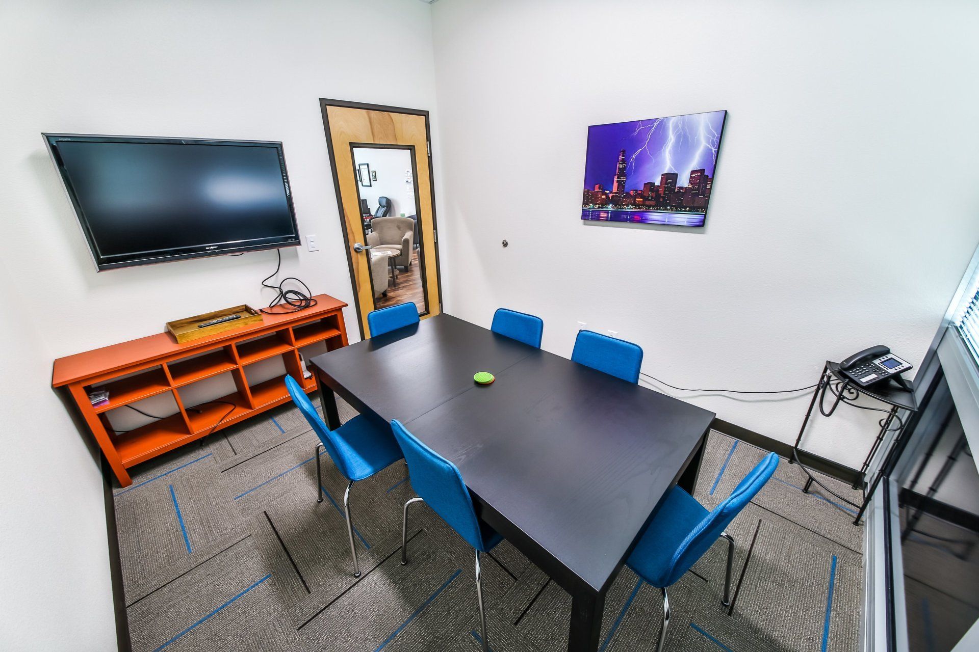 A conference room with a table and chairs and a flat screen tv.