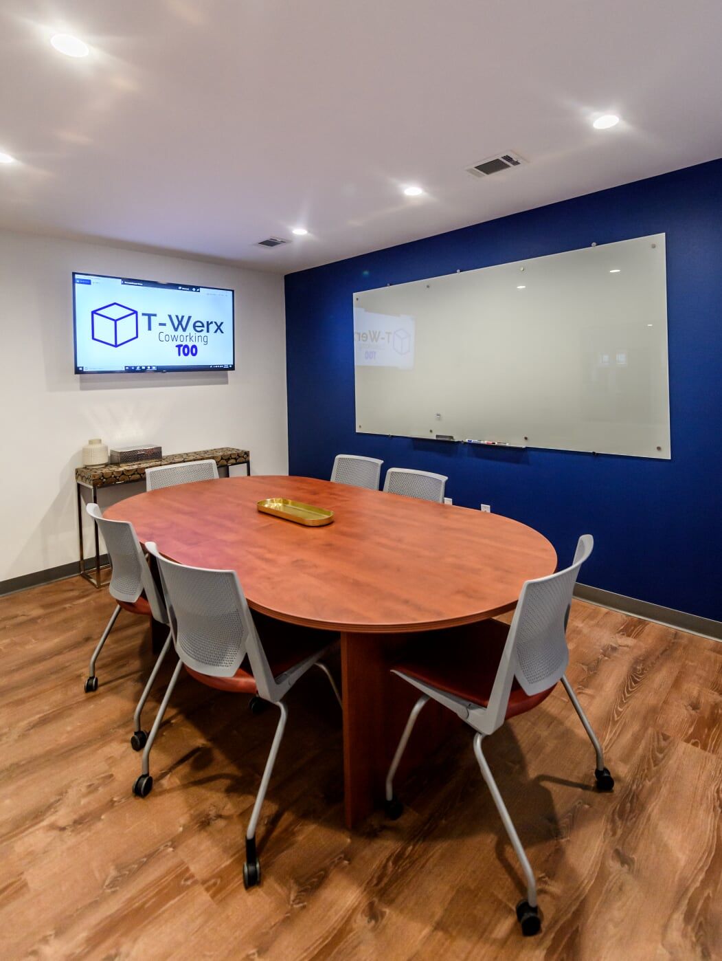 A conference room with a round table and chairs and a whiteboard.