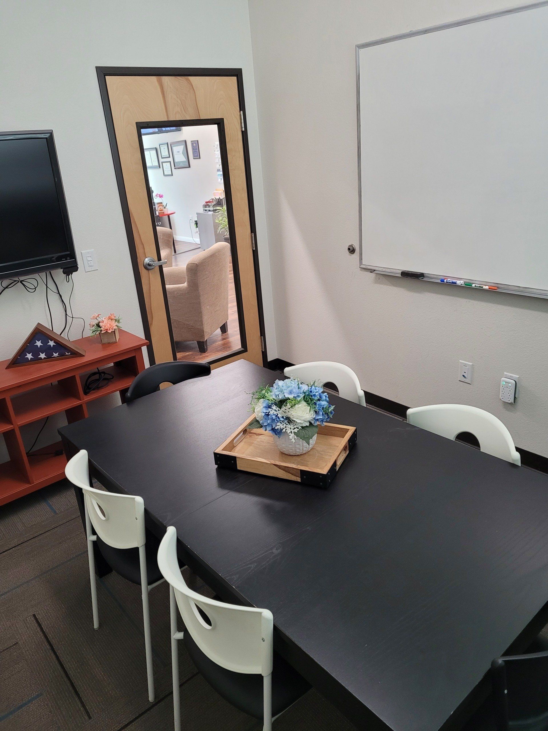 A conference room with a table and chairs and a whiteboard