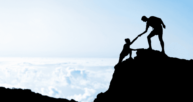 A man is helping another man climb a mountain.