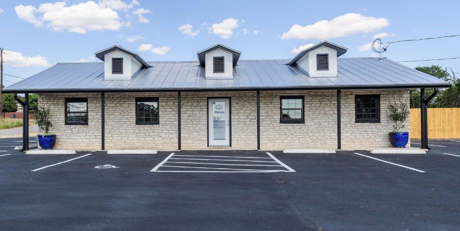 A brick building with a metal roof and a parking lot in front of it.