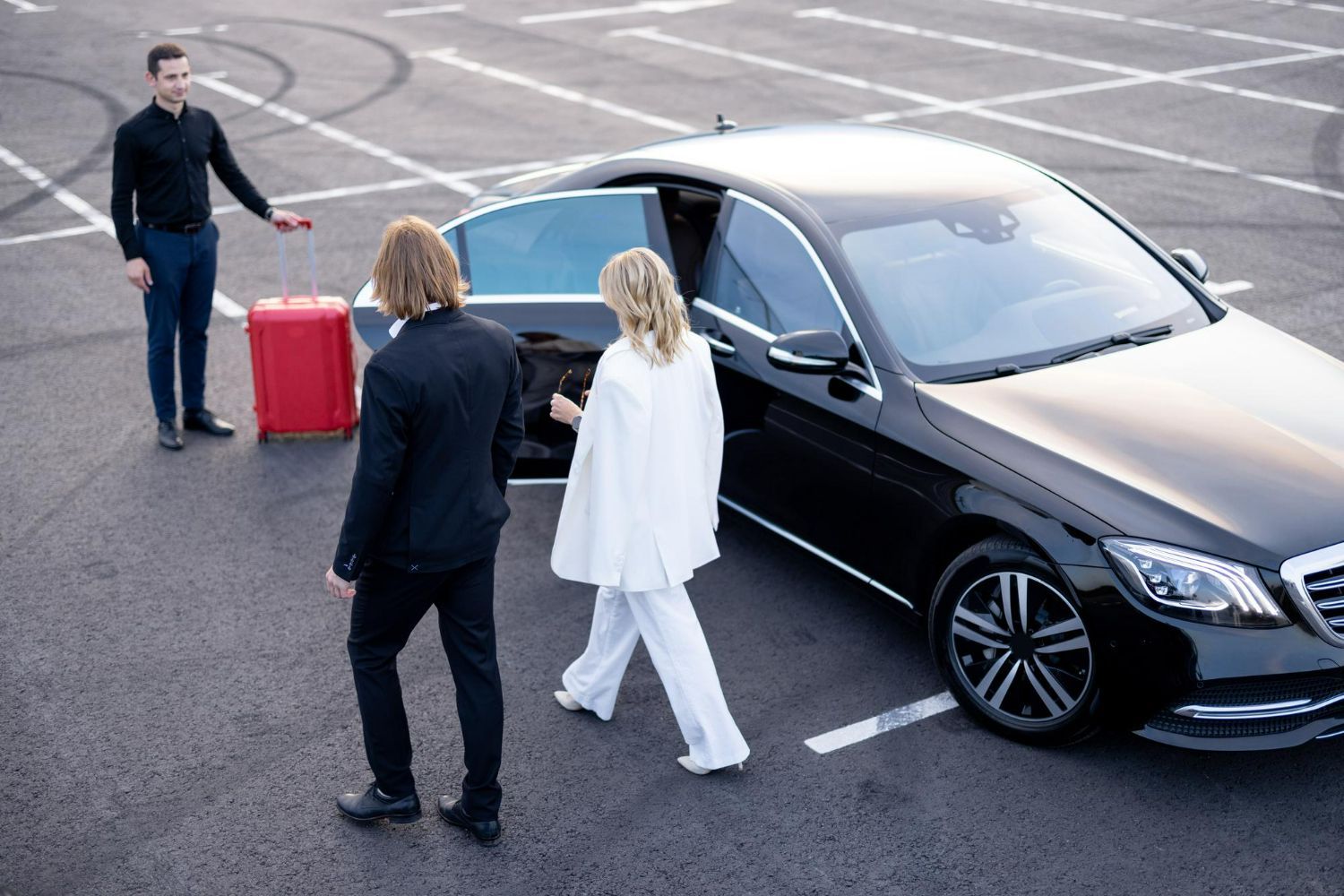 A man and a woman are getting into a car in a parking lot.