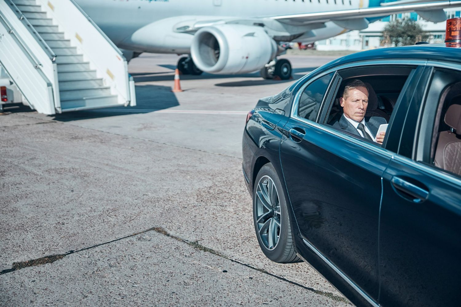 A man is sitting in a car next to an airplane.