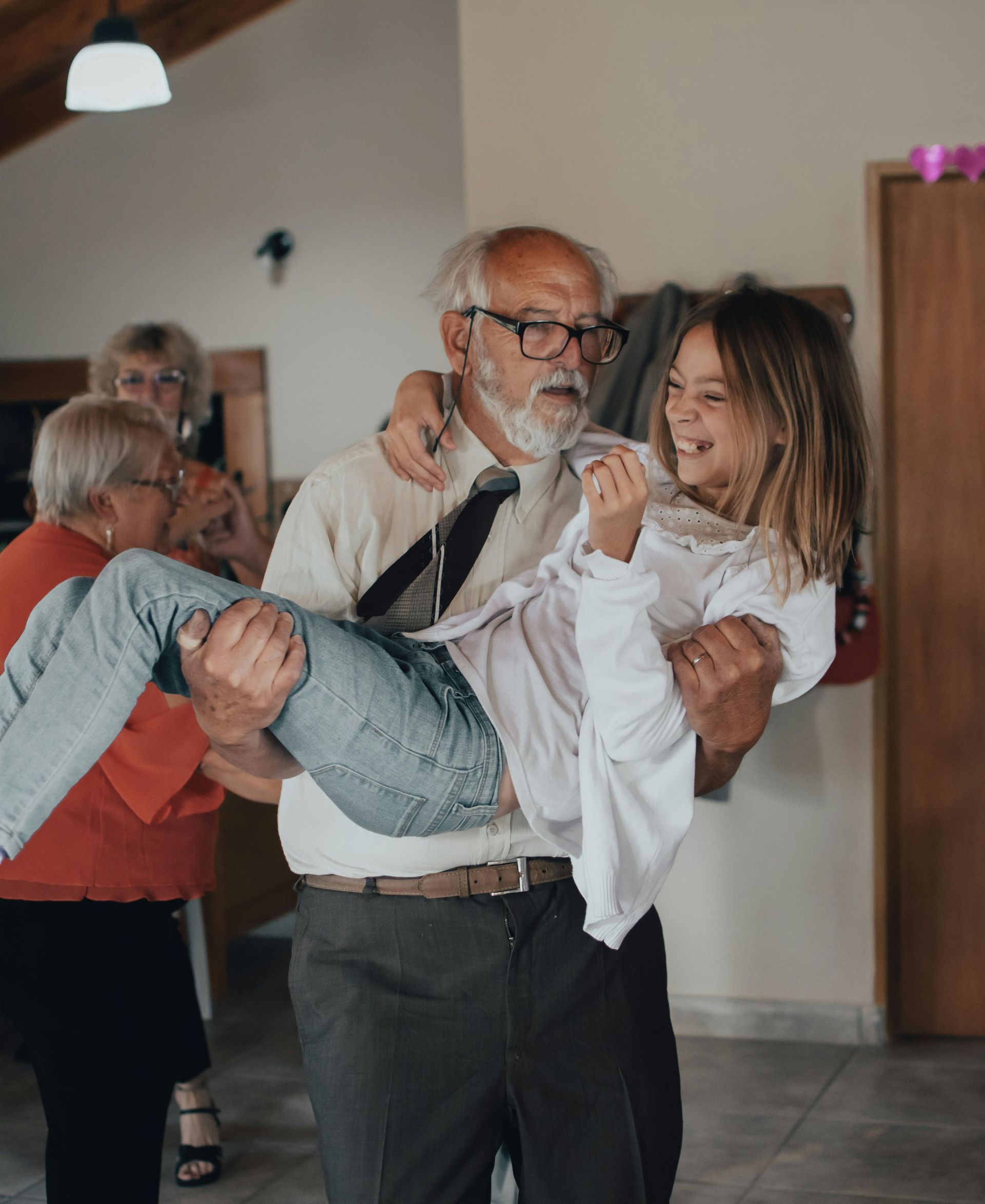 A man is carrying a little girl in his arms.