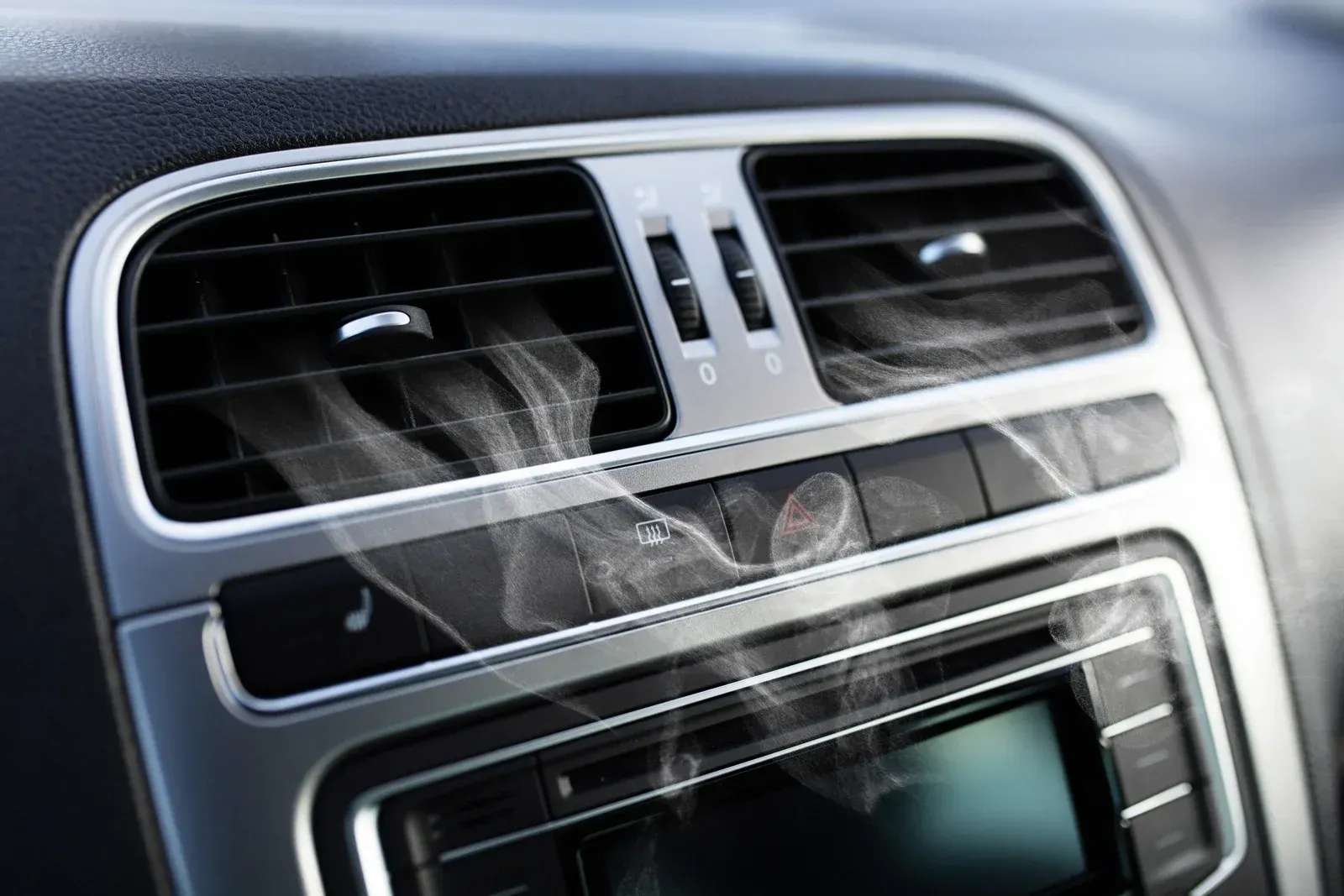 Car dashboard with air vents and visible vapor.