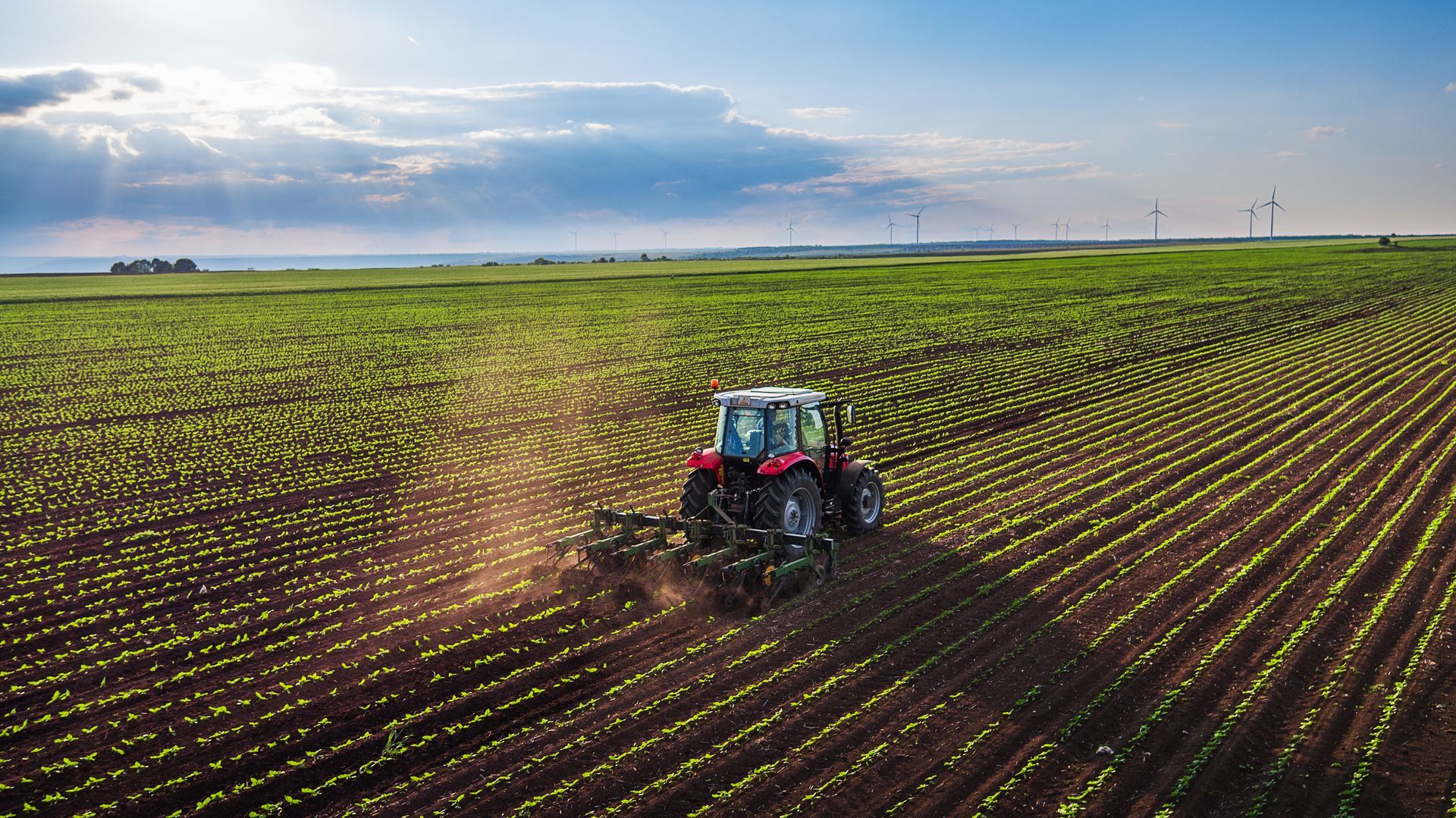a tractor is plowing a field with windmills in the background