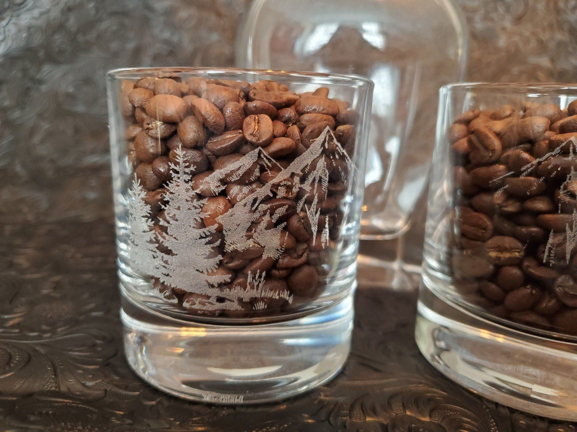 A glass filled with coffee beans with a tree on it
