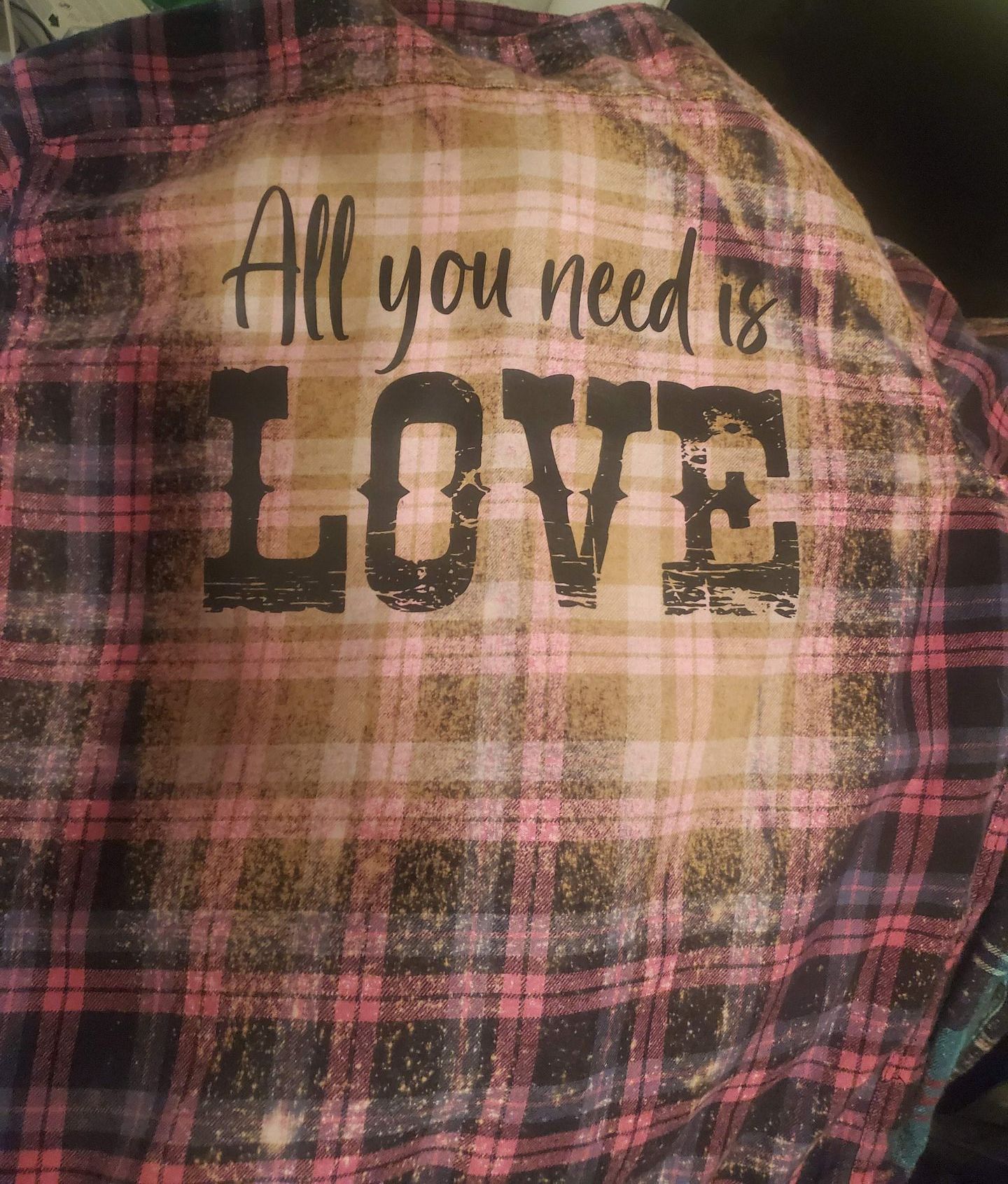 A plaid shirt with the words `` all you need is love '' on it.
