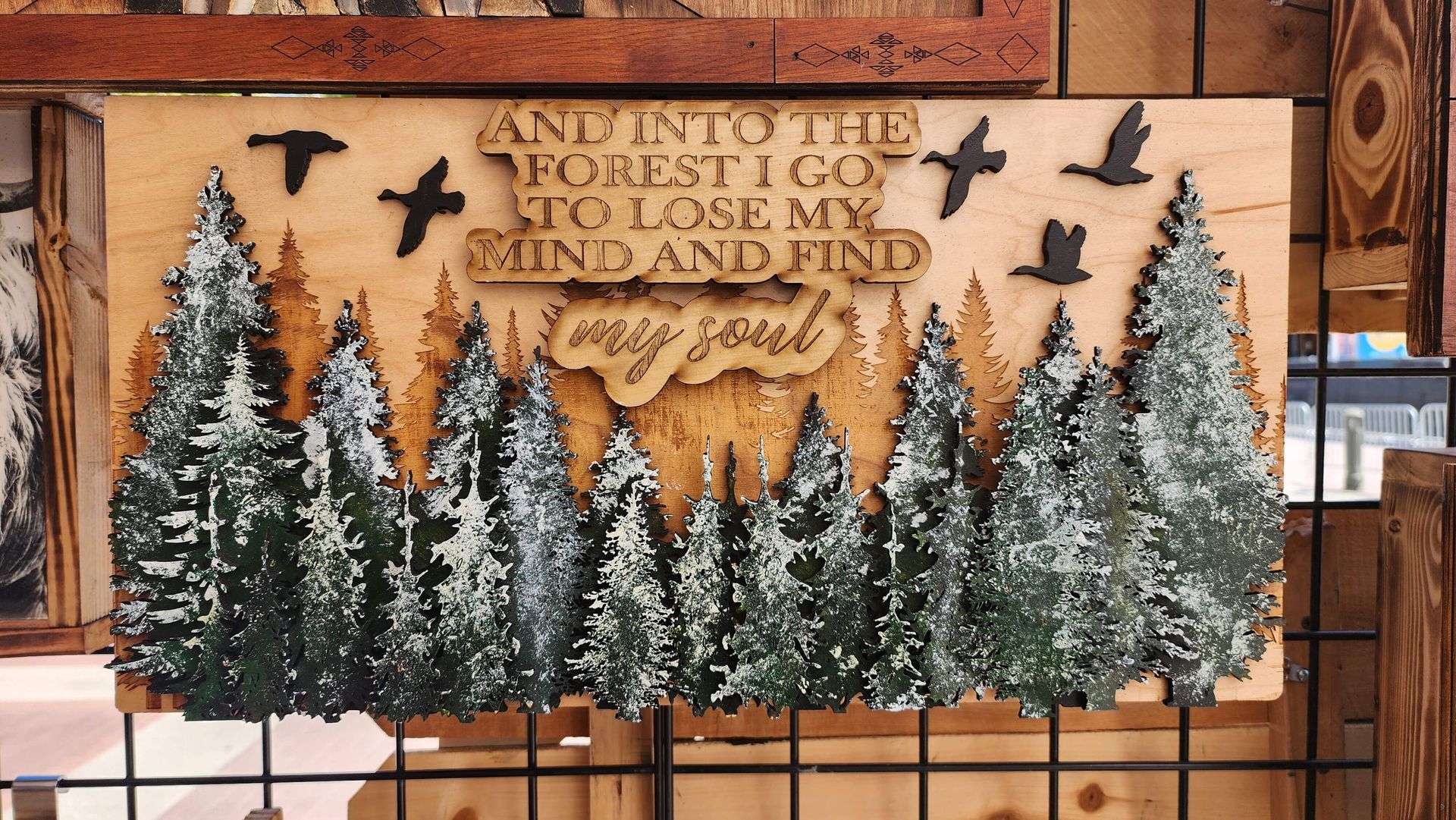 A wooden sign with trees and birds on it that says `` and into the forest i go to lose my mind and find my soul ''