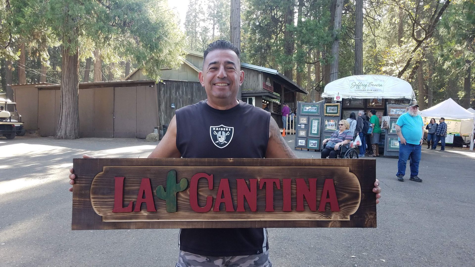 A man is holding a wooden sign that says la cantina