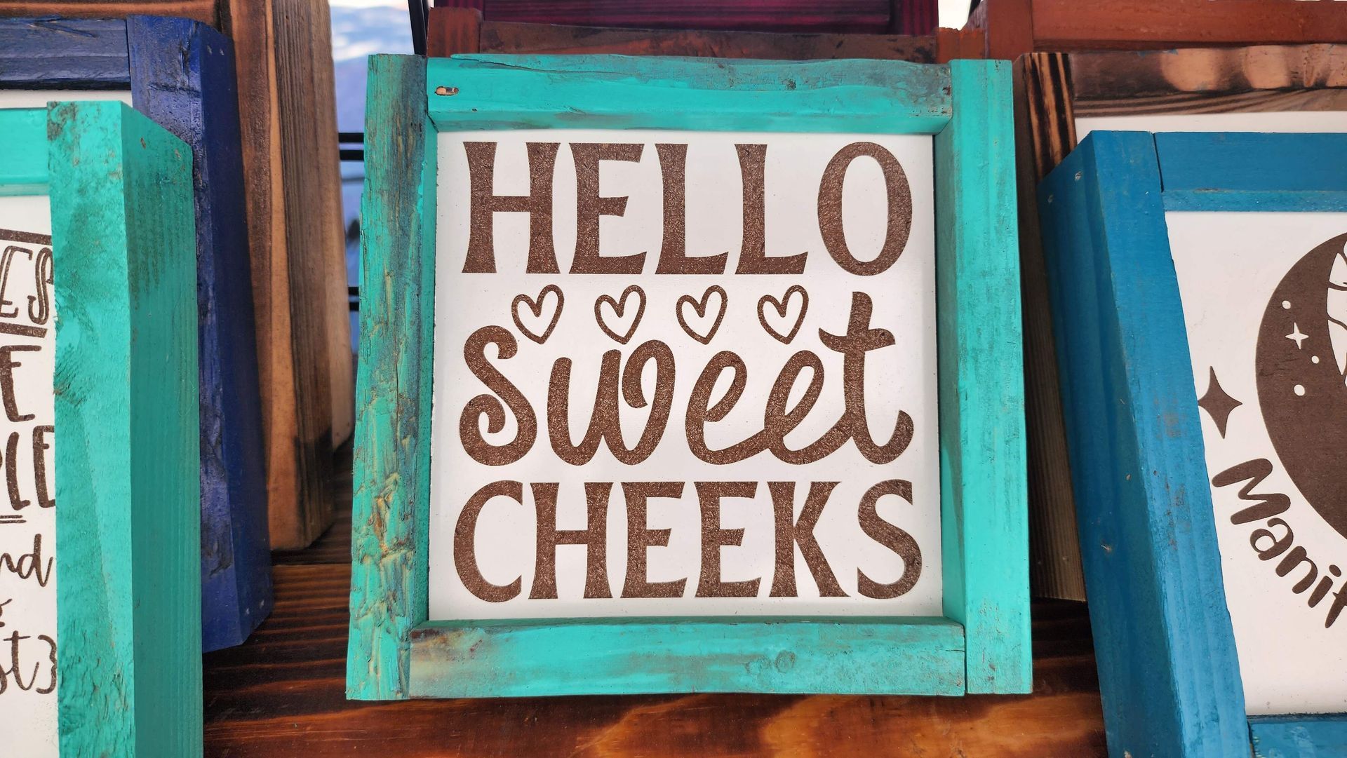 A sign that says hello sweet cheeks is sitting on a wooden table.