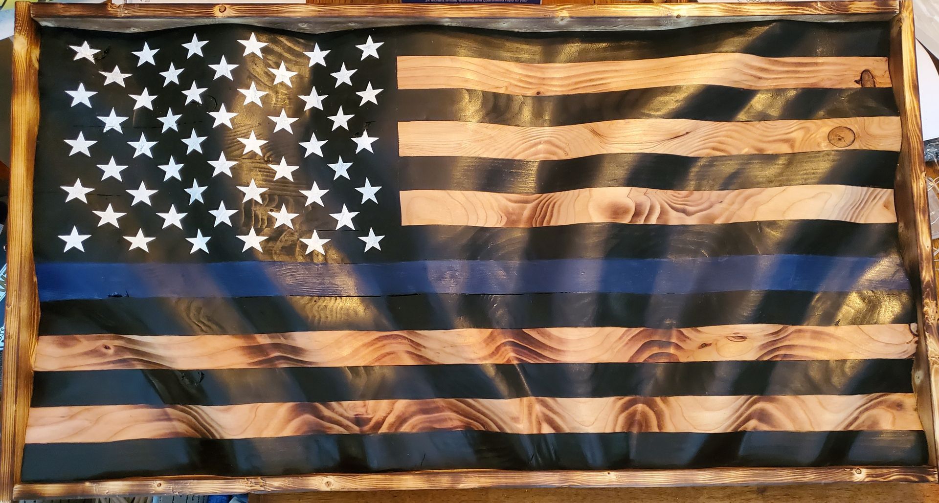 A wooden american flag with a blue stripe on the bottom