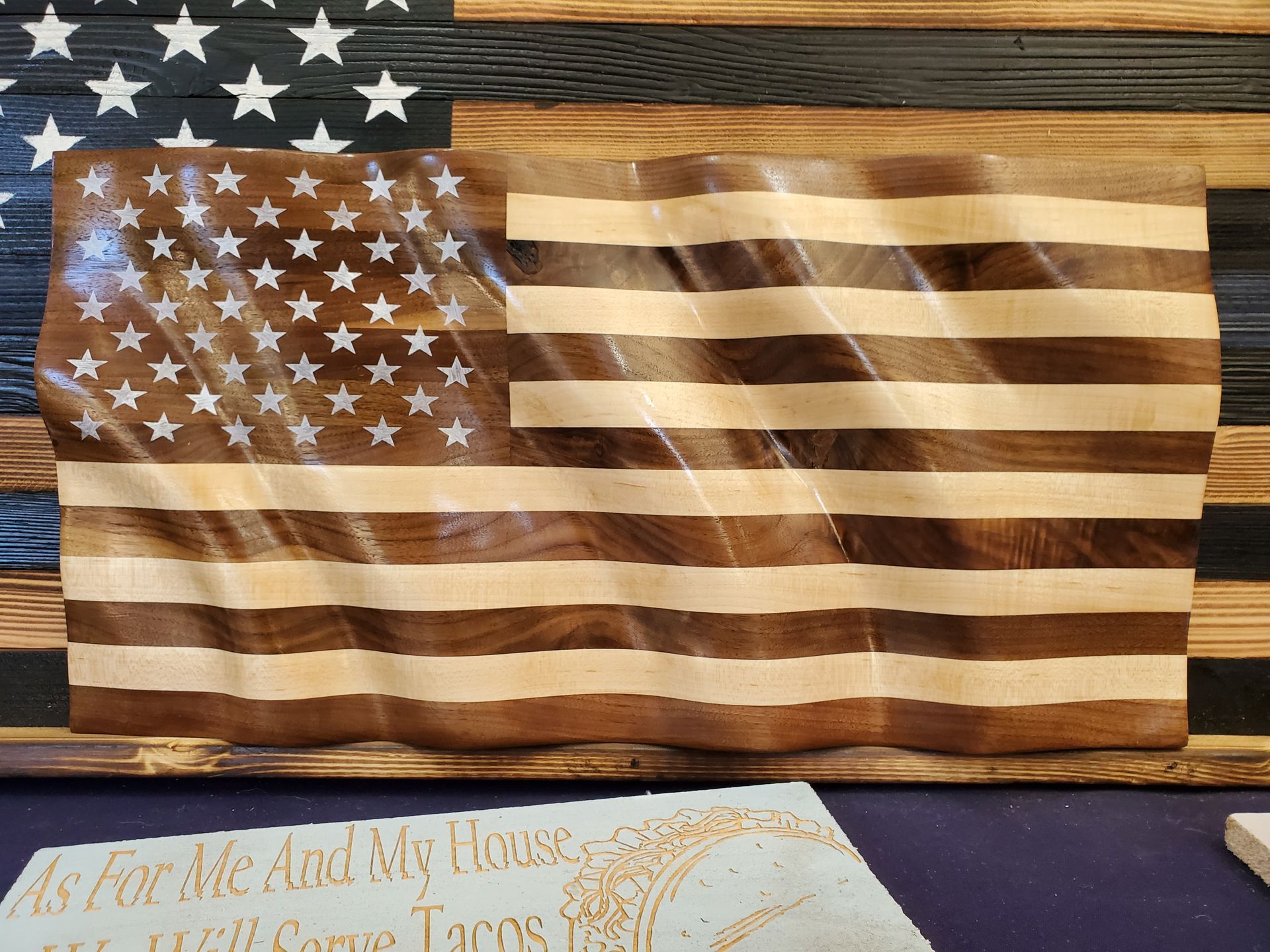 A wooden american flag is hanging on a wooden wall.