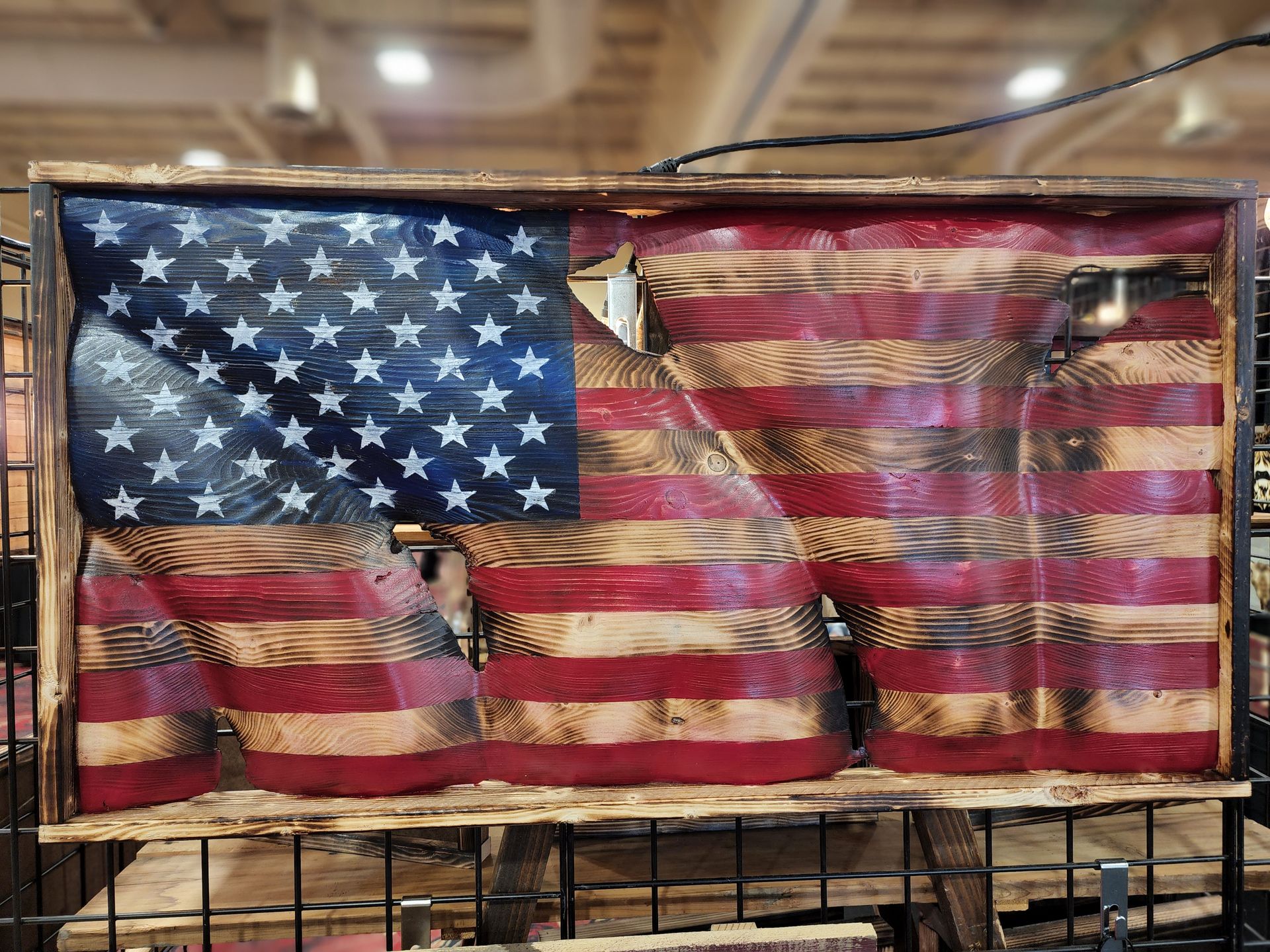 A wooden american flag is sitting on top of a wire fence.