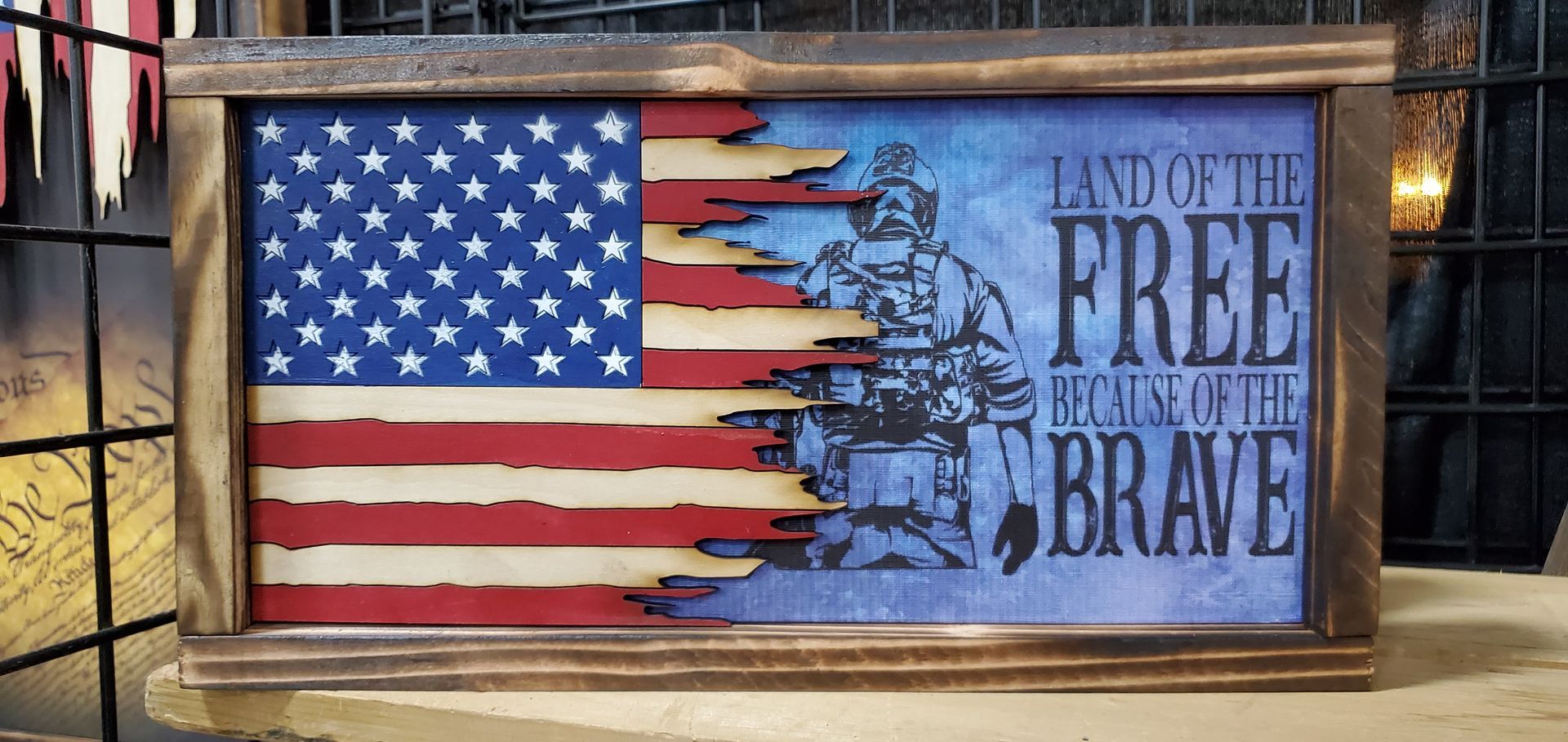 A wooden american flag with the words `` land of the free , home of the brave '' on it.