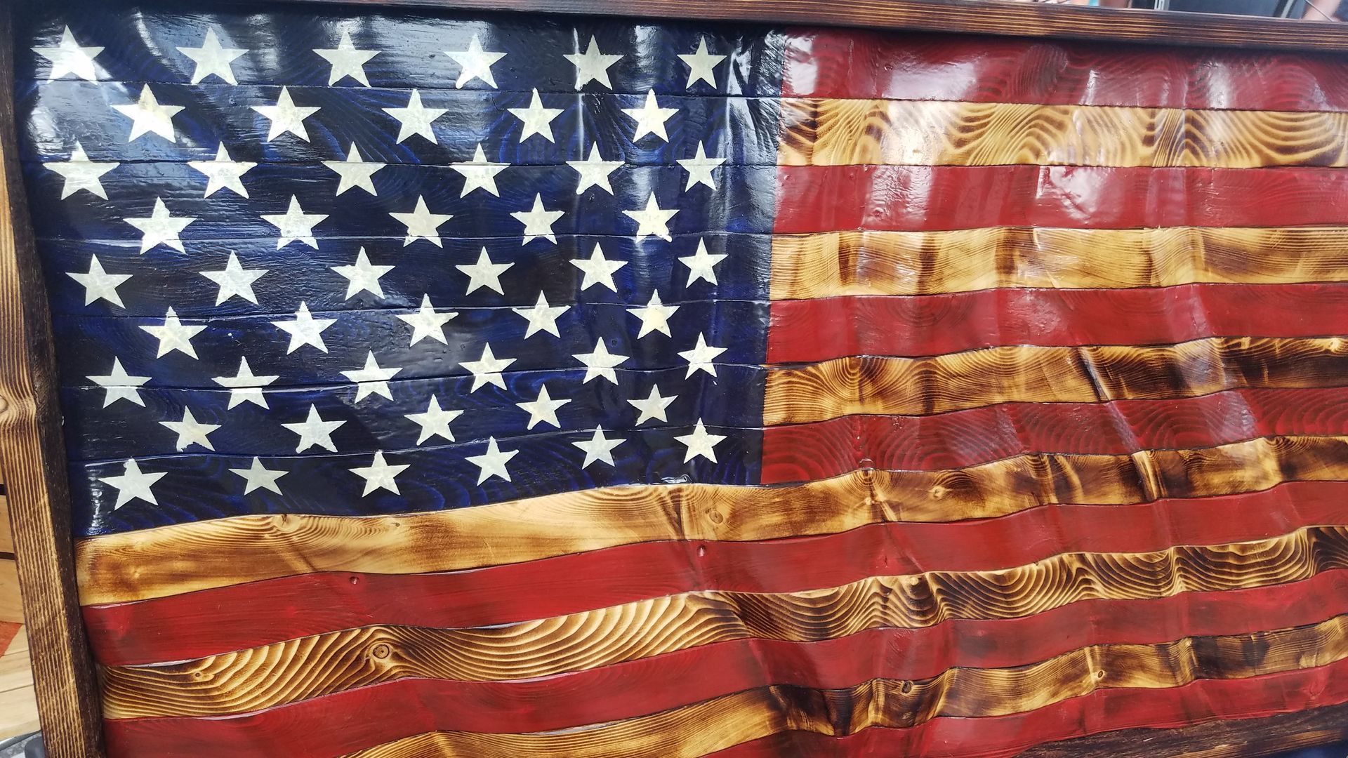 A wooden american flag is hanging on a wall.