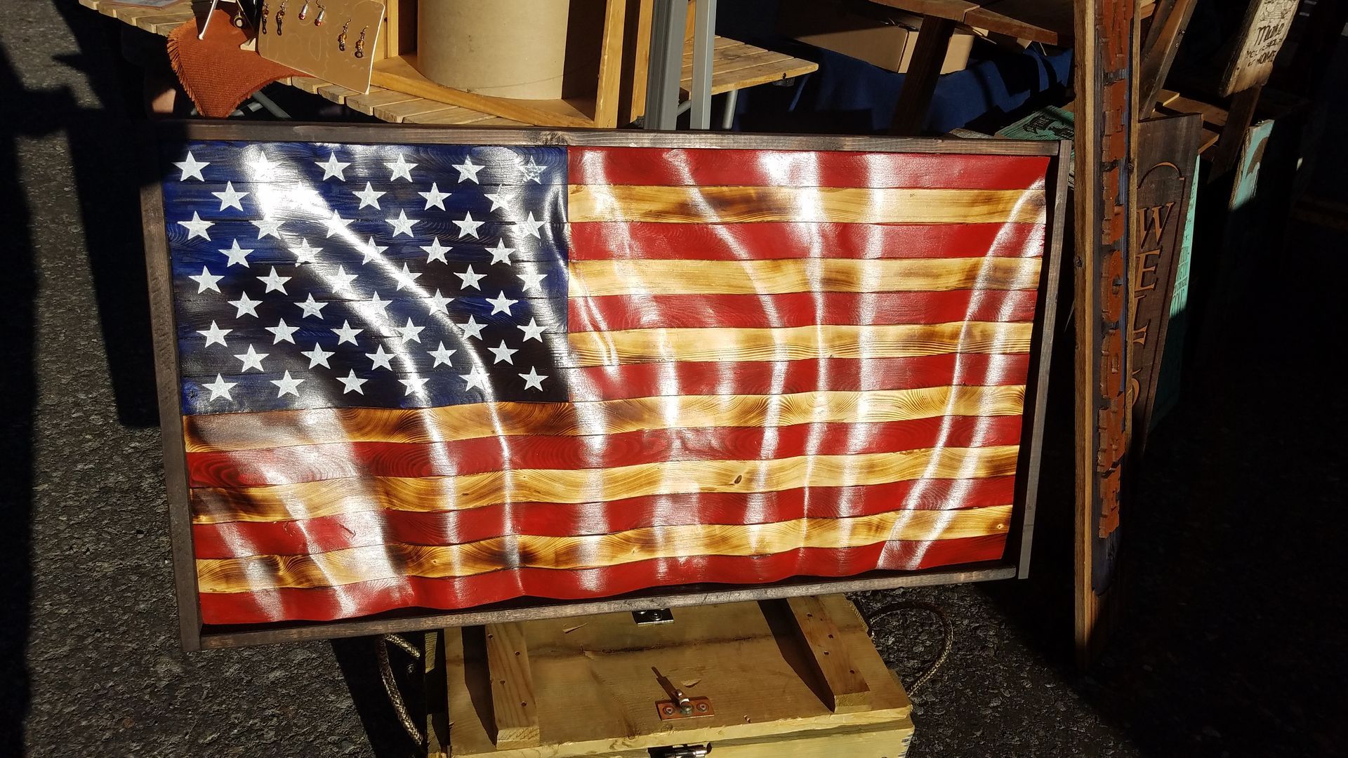 A wooden american flag is sitting on top of a wooden box.