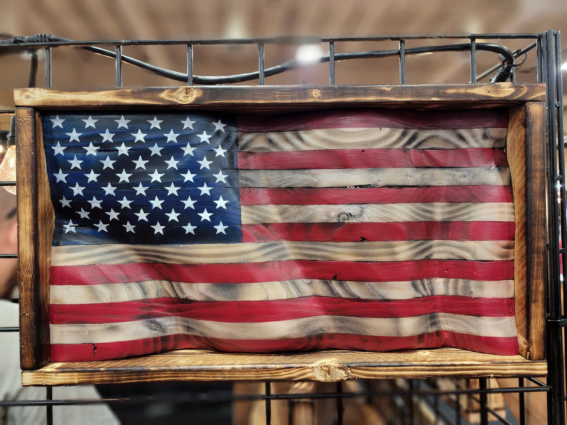 A wooden american flag is hanging on a metal rack.