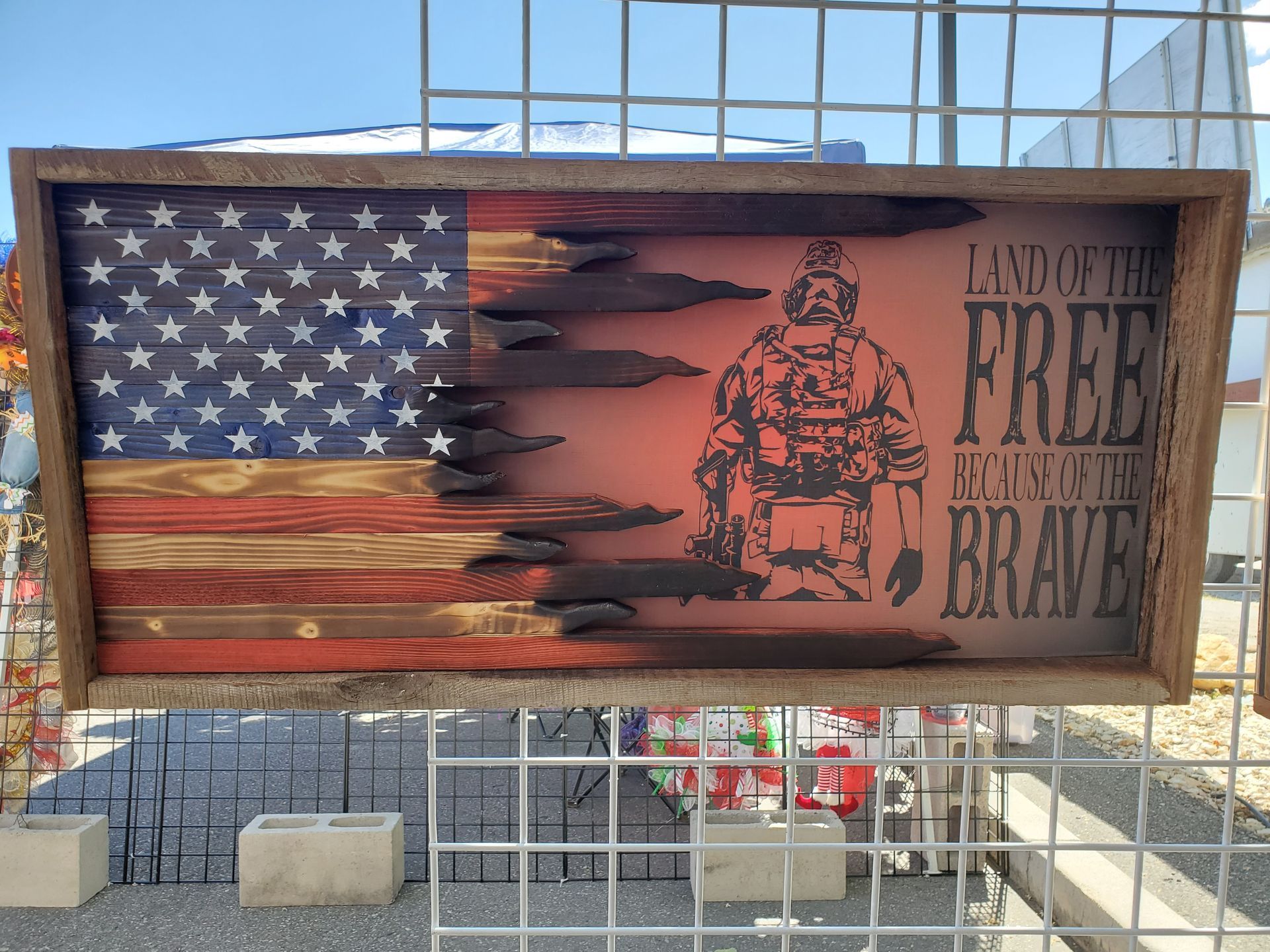 A wooden american flag with bullets and the words land of the free enliven the brave