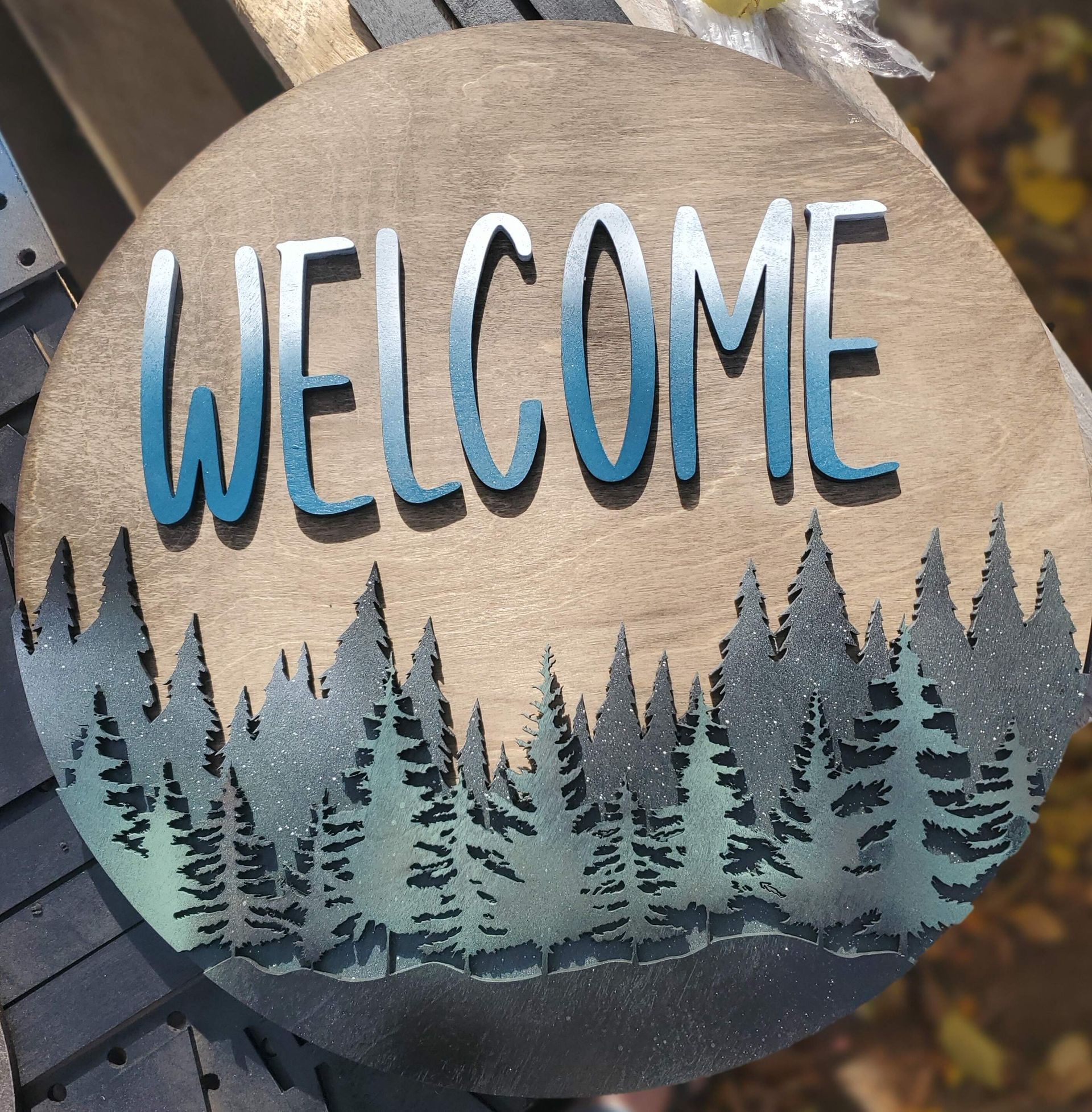 A welcome sign with trees in the background