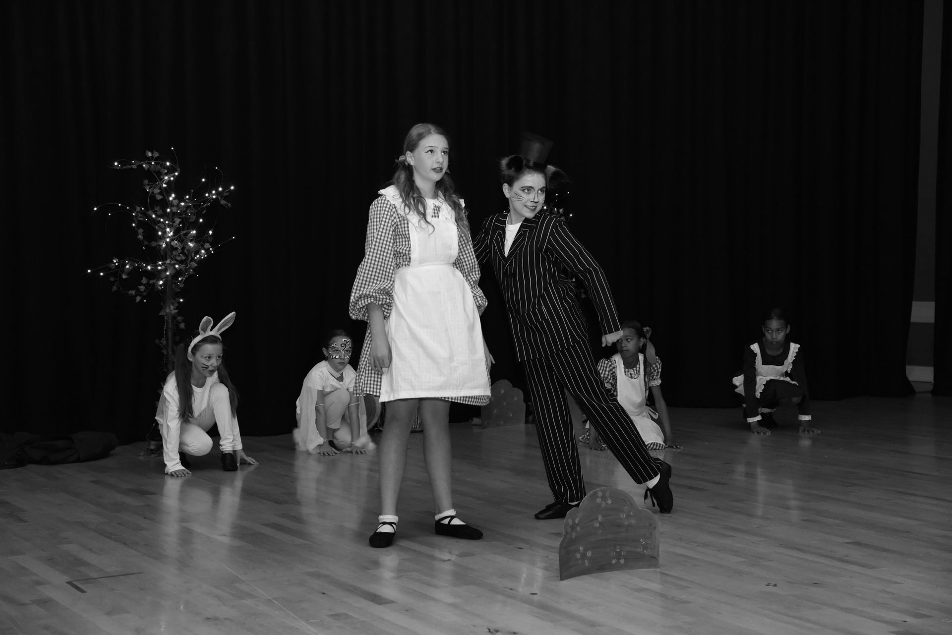 Children performing on stage, dressed as characters from Alice in Wonderland.