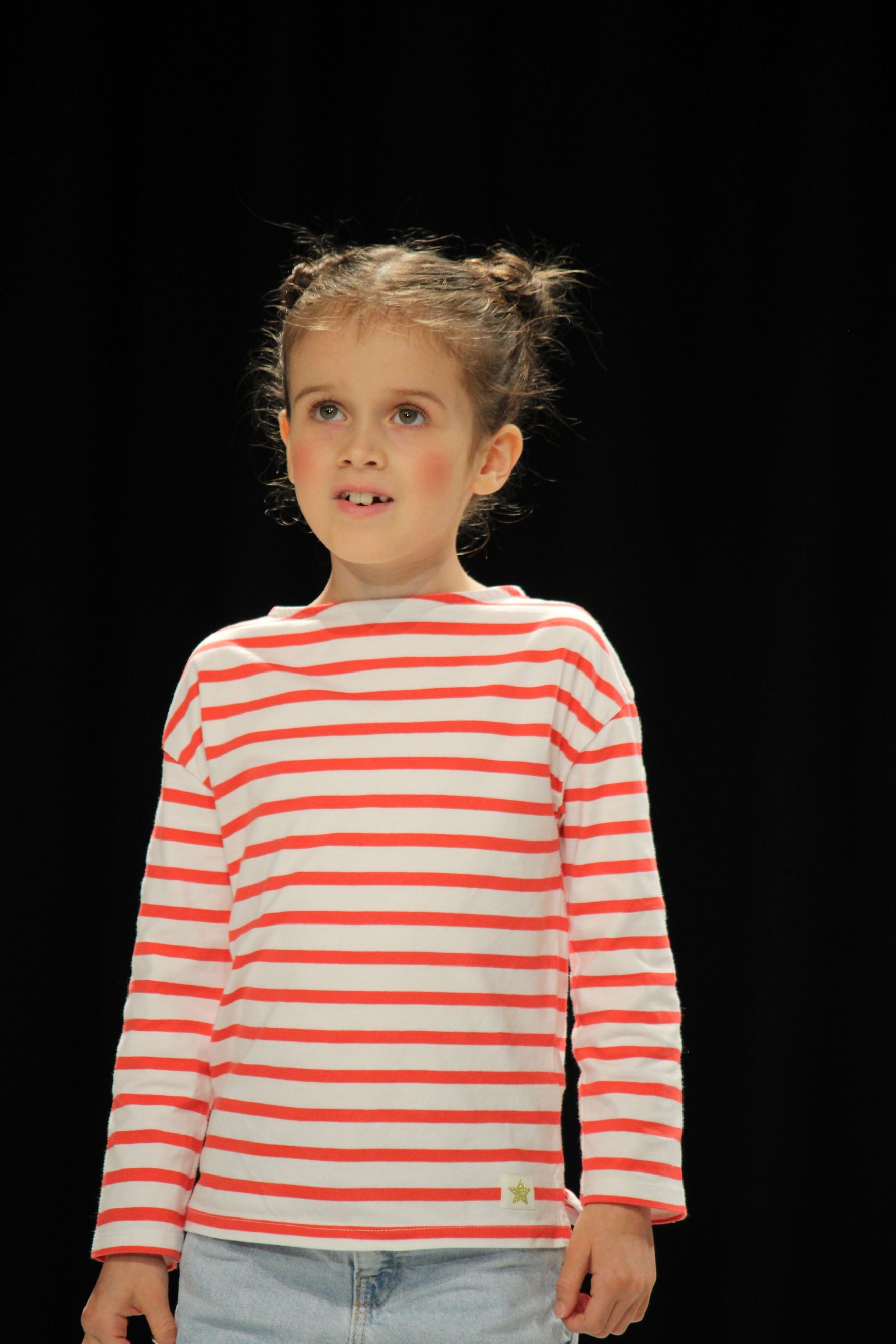 Young child wearing red and white striped shirt, looking up.