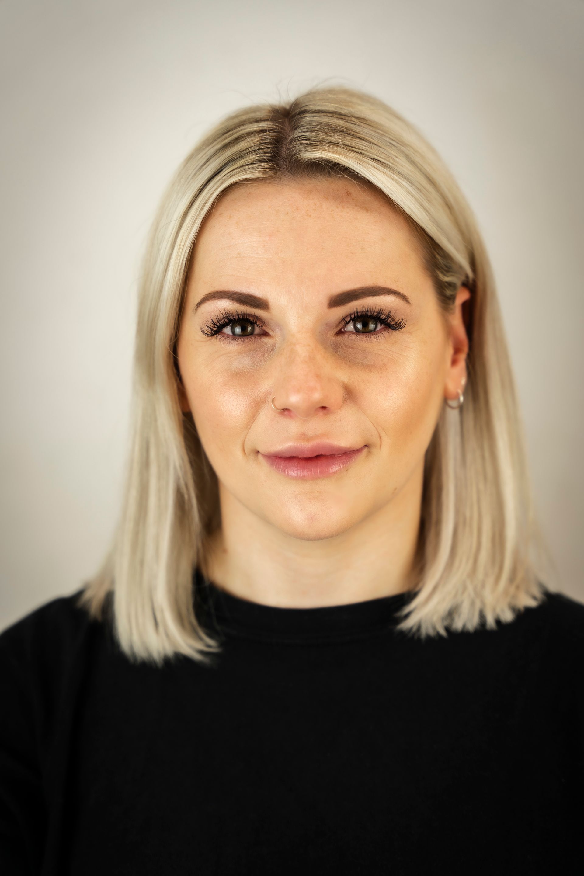 Woman with blonde bob and black top, looking at the camera.