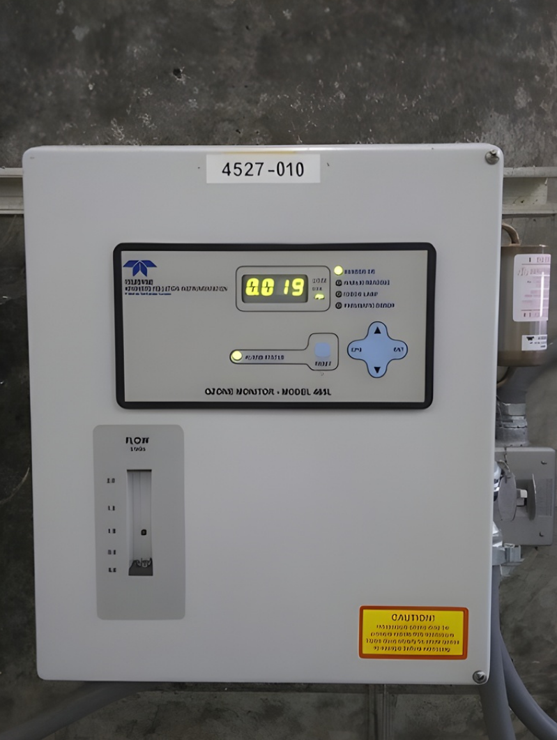 A breakfast sandwich with scrambled eggs, avocado, and bacon on toasted bread, served with a side of greens on a white plate.