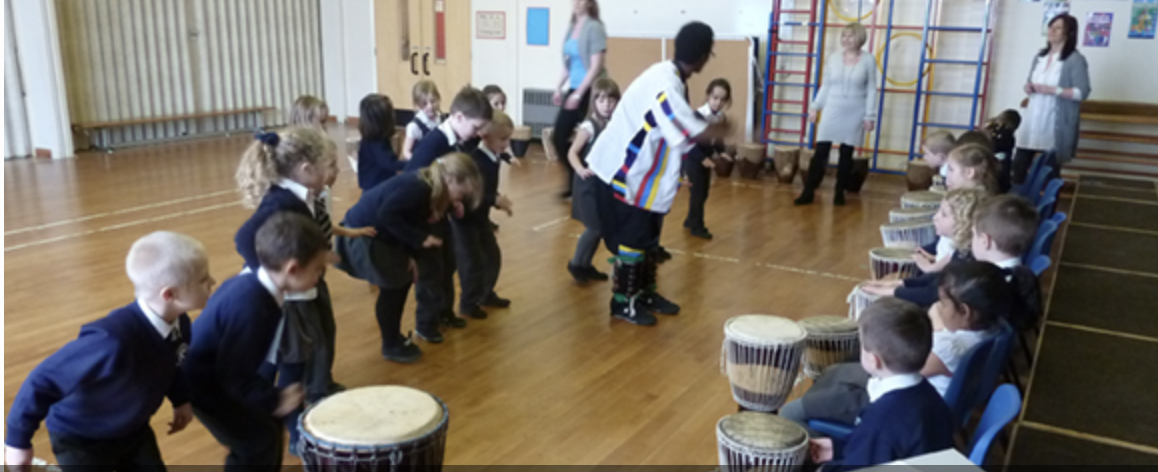 A group of children are playing drums in a gym.