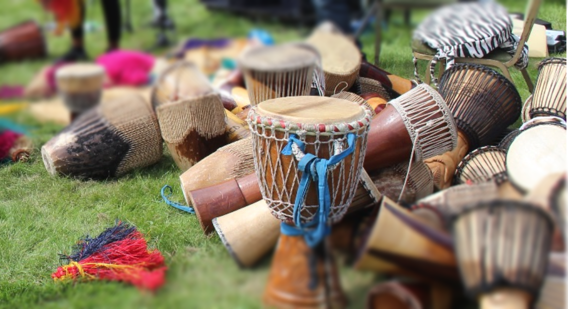 A bunch of  african drums are sitting on top of each other on the grass.