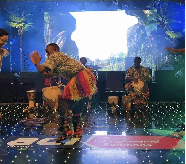 A group of men are dancing on a stage with a bcx logo on the floor