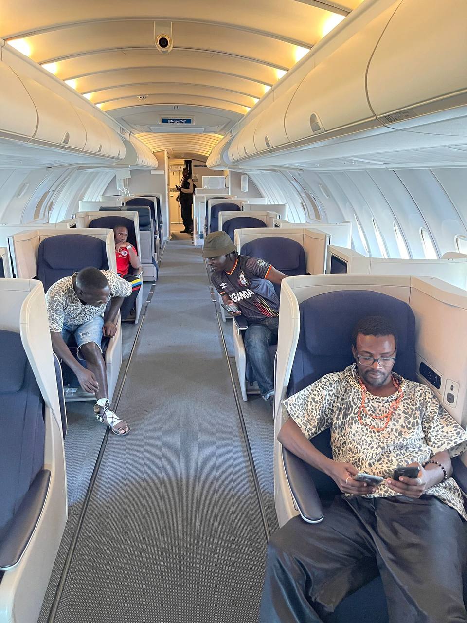 A group of people are sitting on a plane looking at their phones.