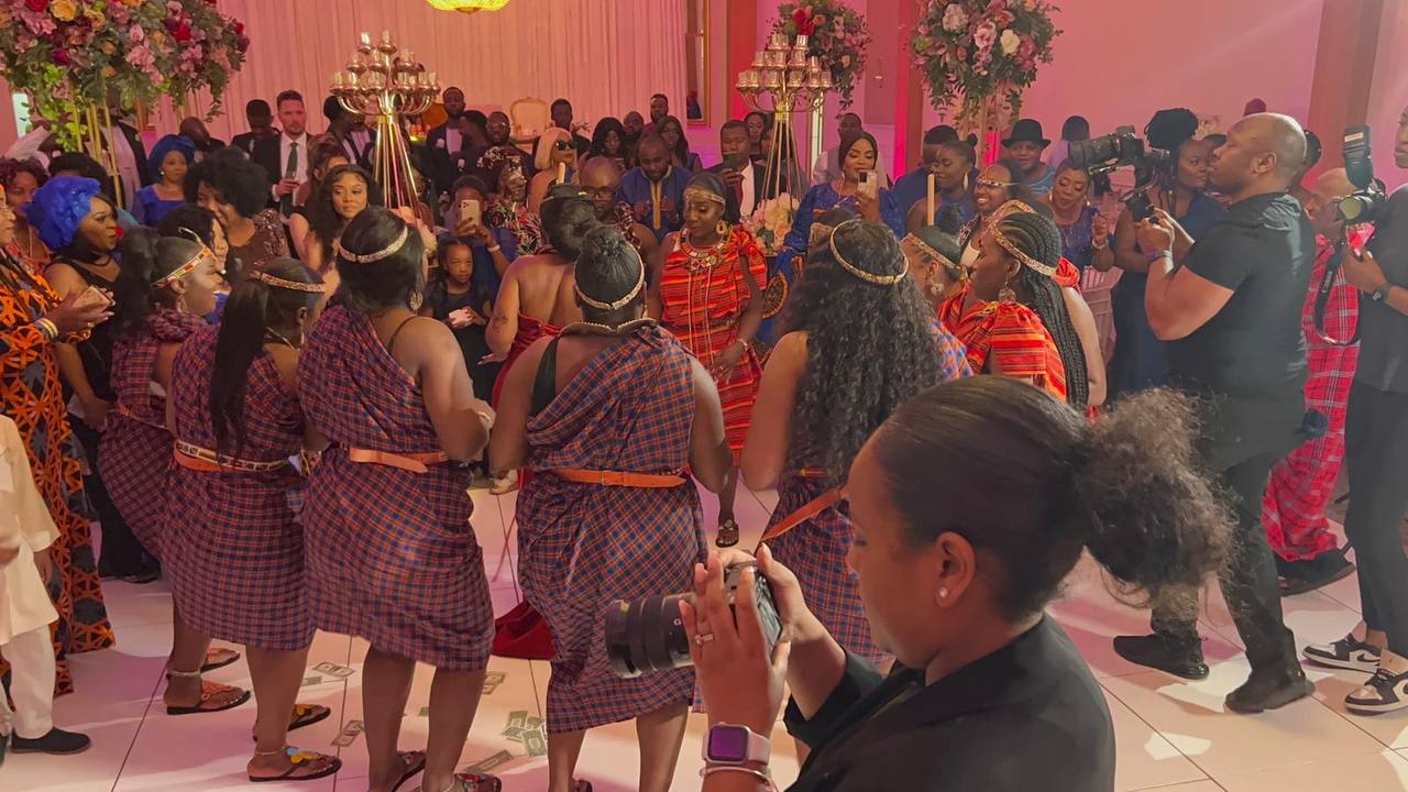 A woman is taking a picture of a group of people dancing at a wedding reception.