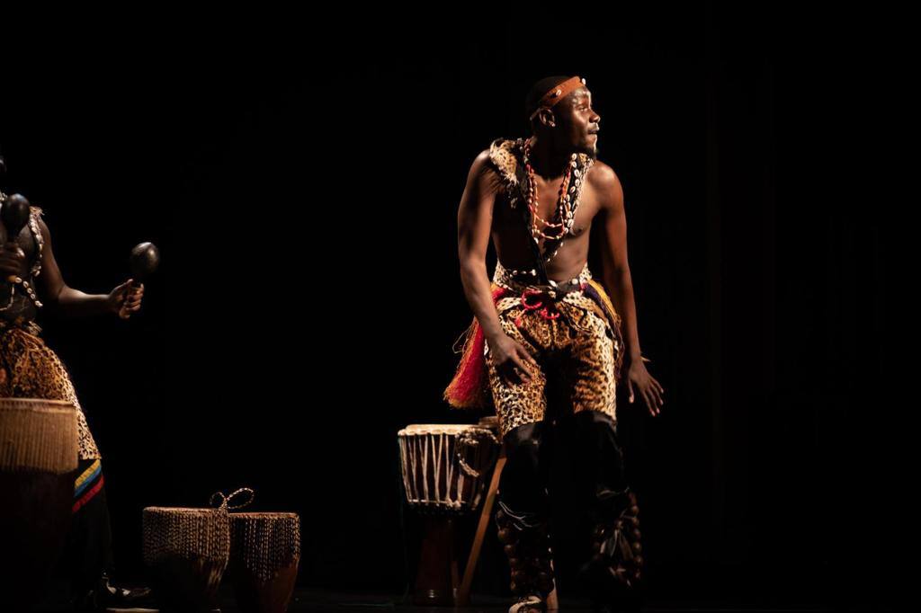 A man is sitting on a drum in a dark room.
