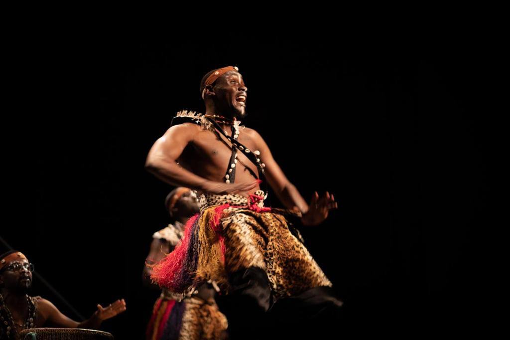 A dancer is sitting on a woman 's lap in a dark room.