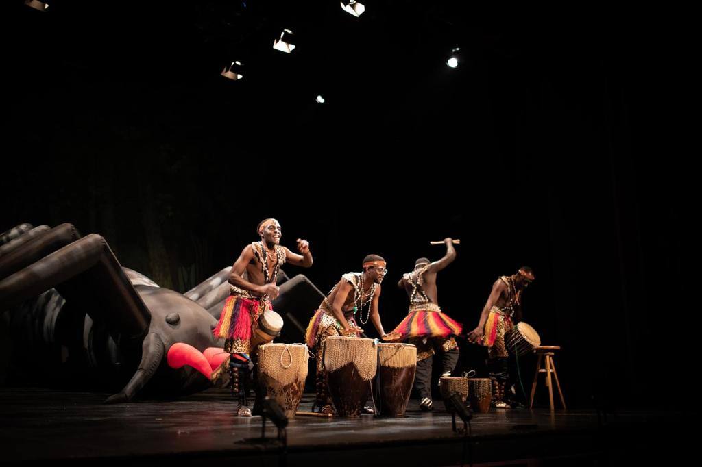 A group of performers are playing drums on a stage.