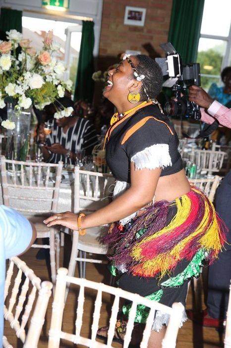 A woman in a colorful skirt is dancing in a room with chairs.
