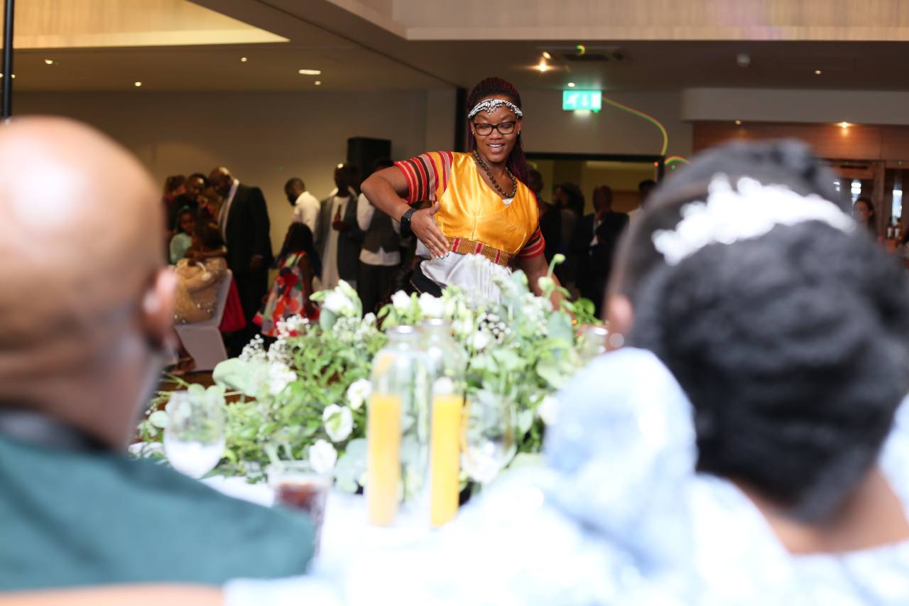 A woman in a yellow shirt is standing in front of a table
