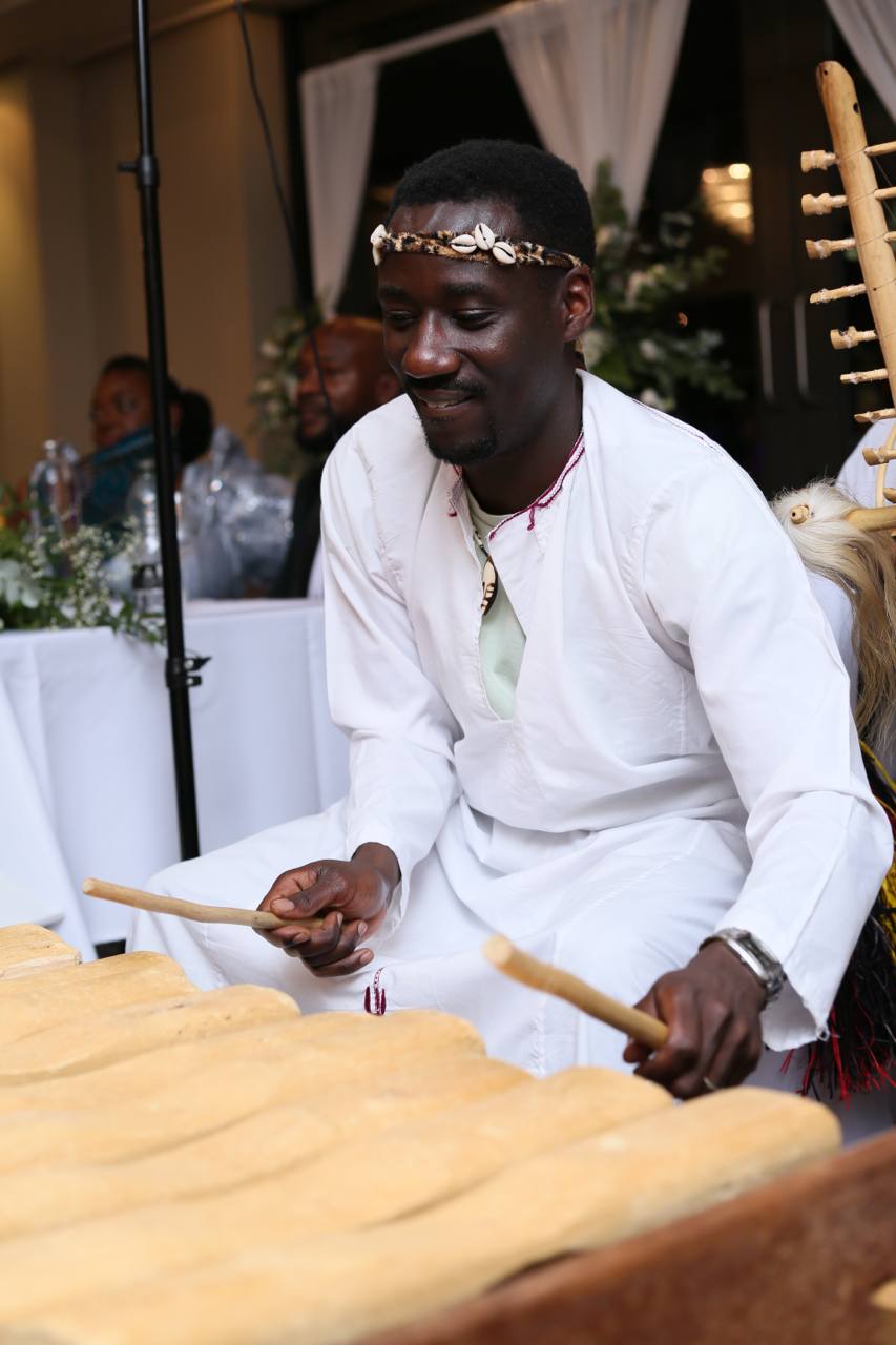 A man in a white shirt is playing a xylophone